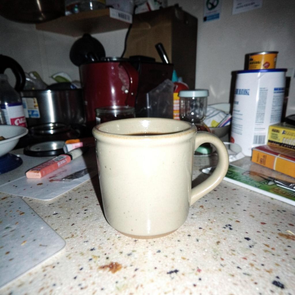 Uploaded phone photo: a ceramic mug on a cluttered kitchen counter